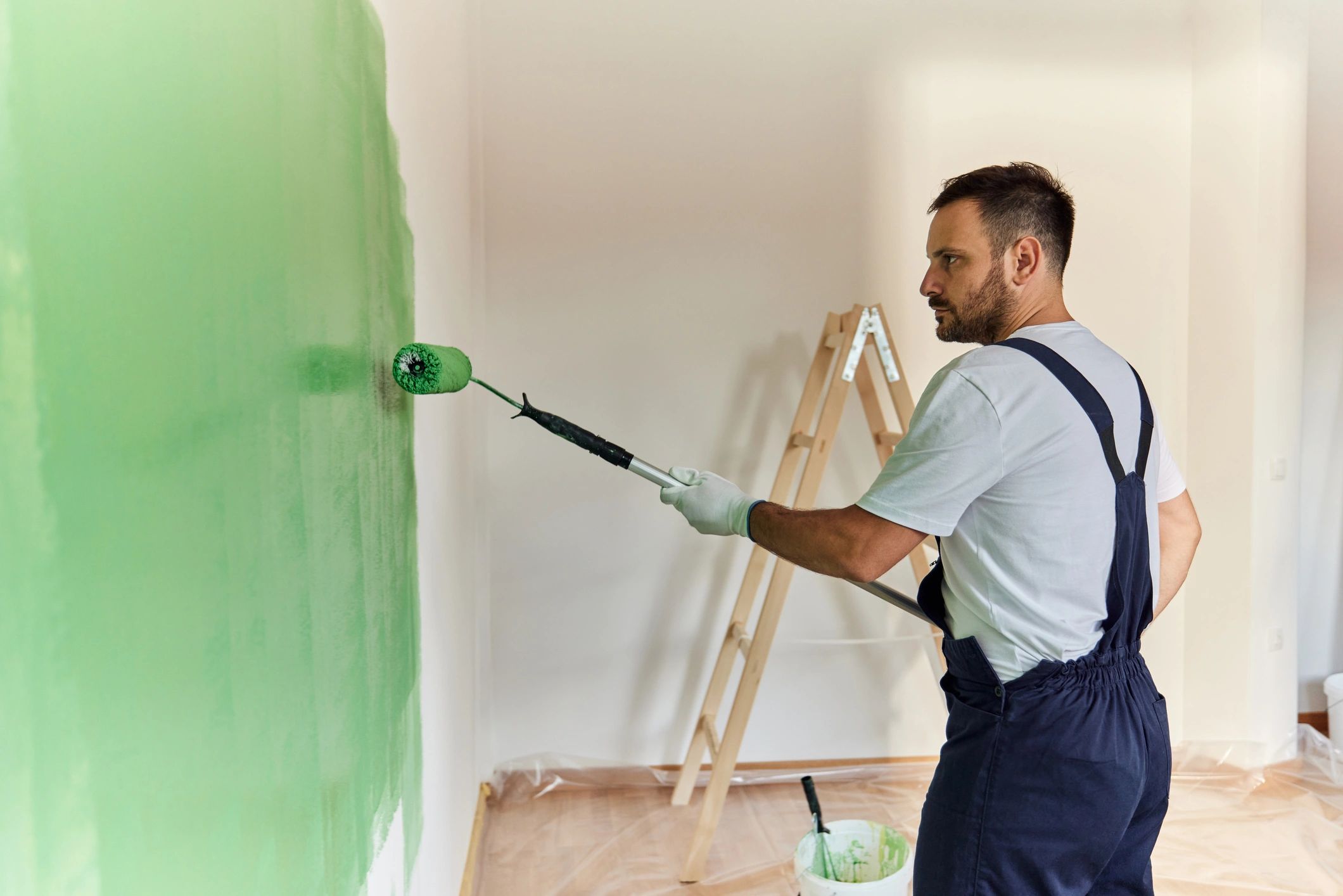 Painter applying green paint to an interior wall