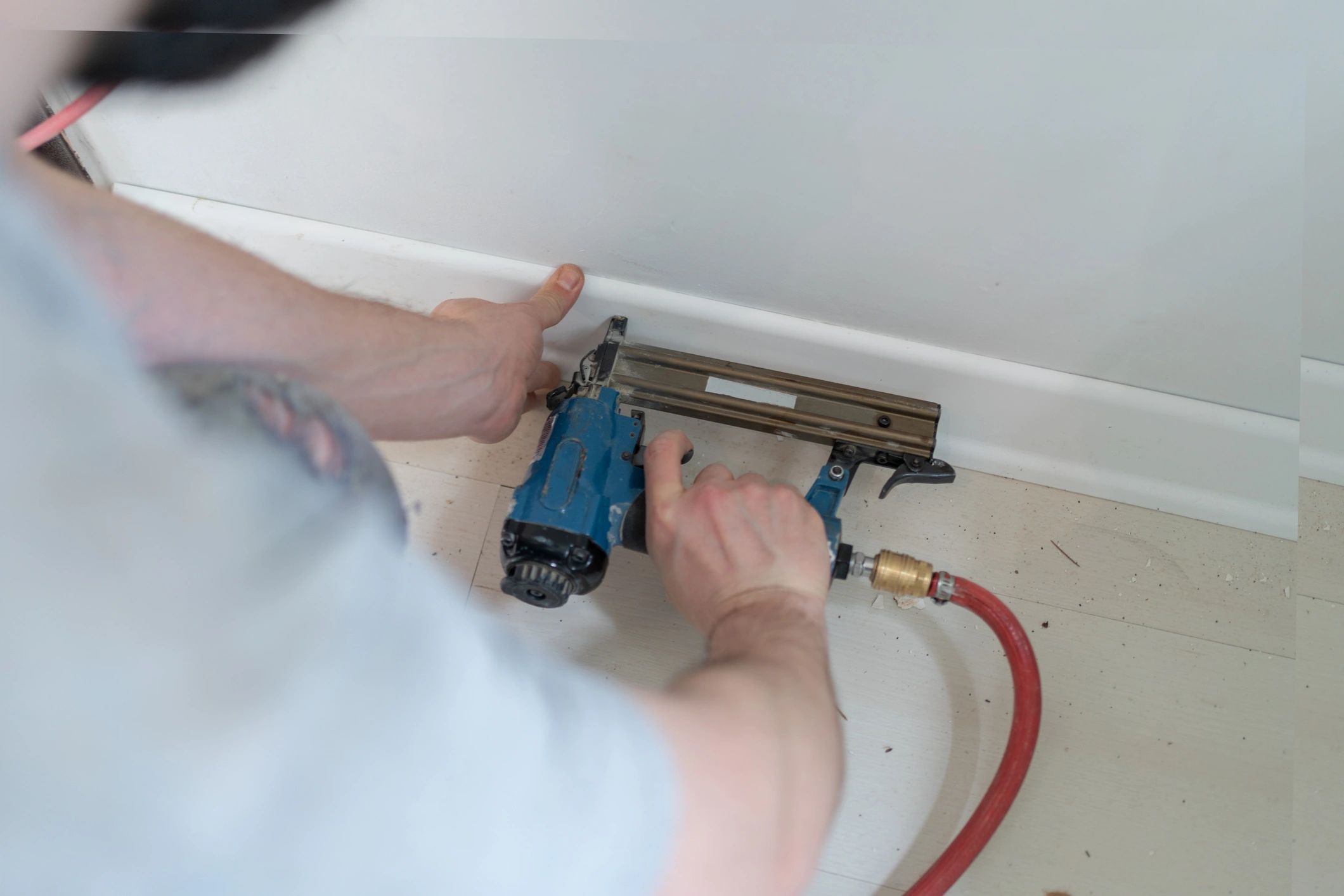 Carpenter installing skirting with nail gun