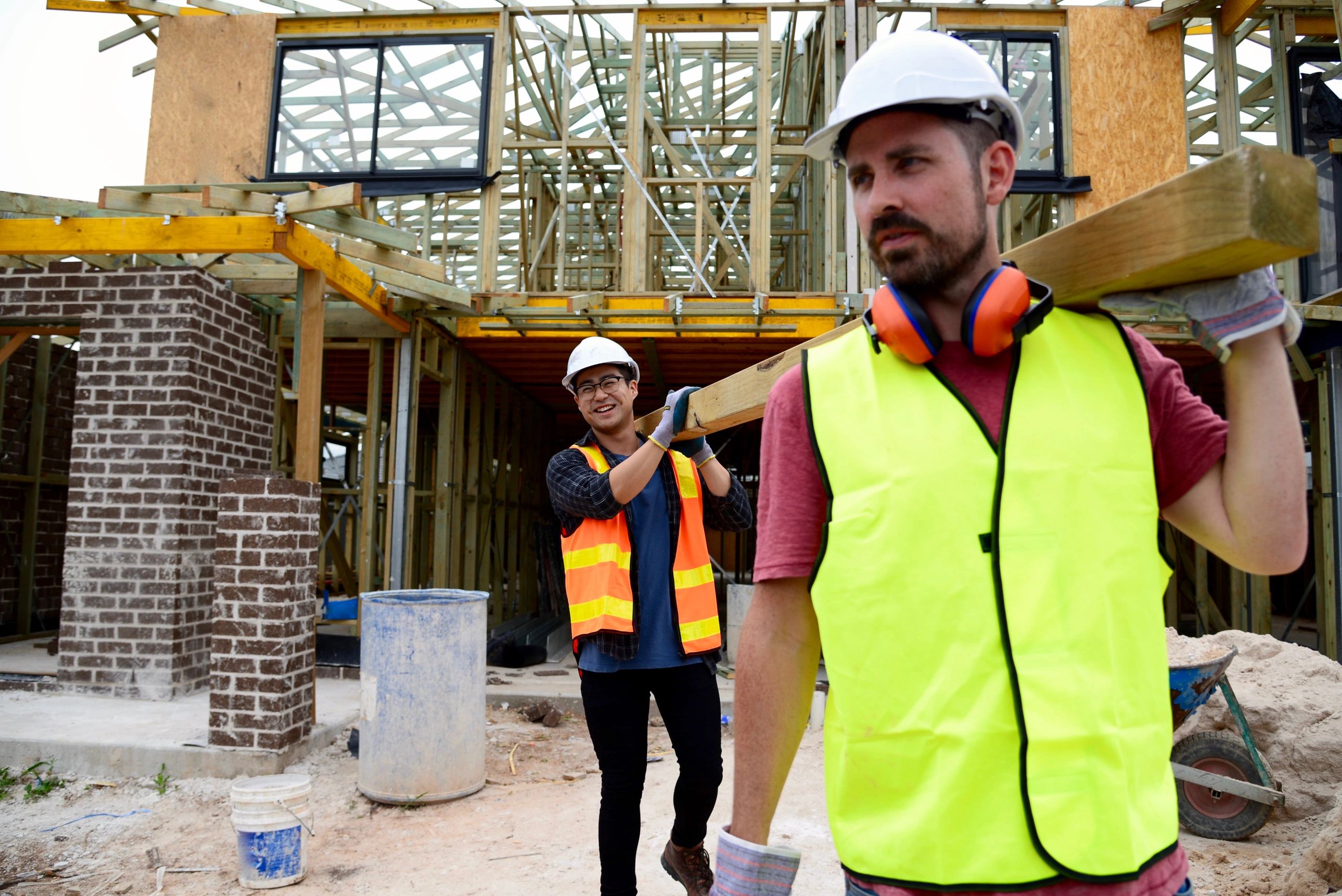 Construction workers carrying timber on a job site